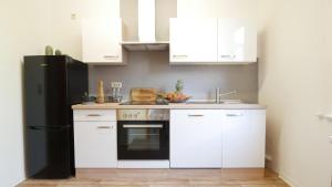 uma cozinha com armários brancos e um frigorífico preto em EUPHORAS - Top ausgestattete Ferienwohnung mit 105 qm und 3 Schlafzimmern em Clausthal-Zellerfeld