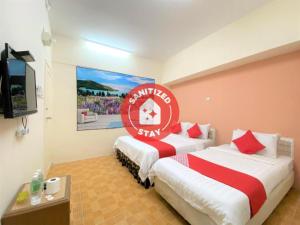2 camas en una habitación con un cartel en la pared en OYO 89540 B Hotel Penang en Bayan Lepas