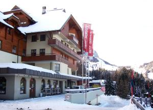 eine Skihütte im Schnee mit einem Gebäude in der Unterkunft Appartement Sonja Nassfeld in Sonnenalpe Nassfeld