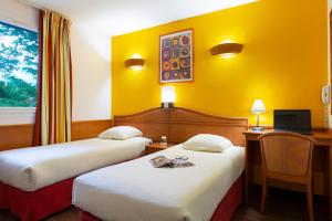 a hotel room with two beds and a desk at B&B HOTEL Amneville-les-Thermes in Amnéville
