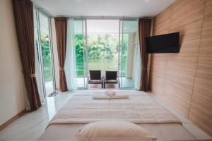 a bedroom with two beds and a large window at Erachon Raft Resort in Kanchanaburi