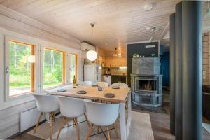 a kitchen and dining room with a wooden table and chairs at Lähderinne - Beachfront 2 bedroom log cabin, private beach & sauna in Puolanka