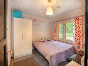 a small bedroom with a bed and a window at Lähderinne - Beachfront 2 bedroom log cabin, private beach & sauna in Puolanka