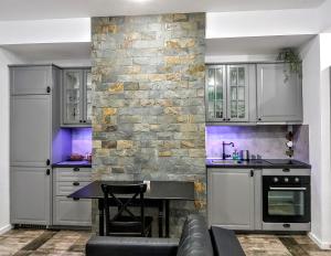 a kitchen with white cabinets and a stone wall at Sinaia Veche in Sinaia