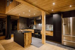 a kitchen with black and stainless steel appliances and wooden ceilings at Chalet Harmonie in Morzine