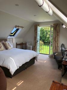 a bedroom with a bed and a large window at The Old School, Idbury, OX7 6RU in Chipping Norton