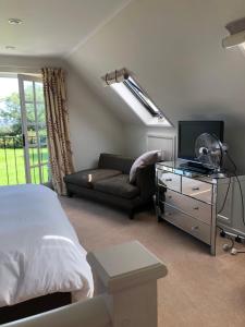 a bedroom with a bed and a couch and a television at The Old School, Idbury, OX7 6RU in Chipping Norton