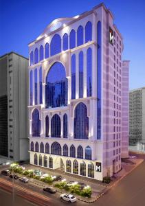 a large white building with blue windows in a city at M Hotel Al Dana Makkah by Millennium in Mecca