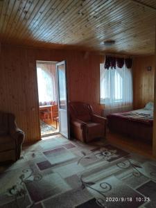 a bedroom with a bed and a couch and a chair at Котедж ,,ТІК" in Tatariv