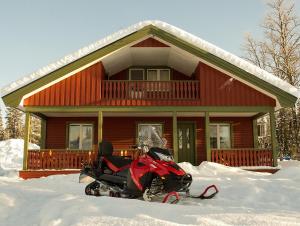 a motorcycle parked in the snow in front of a house at Camp Alta Kiruna in Kiruna