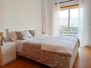 a white bedroom with a large bed and a balcony at Janelas do Douro in Peso da Régua