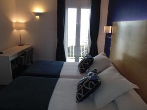 a bedroom with a bed with two pillows and a window at Hotel Llorca in Platja de l’Almadrava
