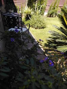 a bench sitting in a garden with purple flowers at Apartamento Laila,Sevilla, in Alcalá de Guadaira