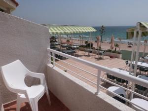a balcony with a white chair and a view of the beach at Hotel Llorca in Platja de l’Almadrava