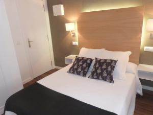a bedroom with a white bed with two pillows on it at Hotel Llorca in Platja de l’Almadrava
