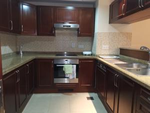 una cucina con armadi in legno e piano cottura. di نزل المارينا - Marina Resident a King Abdullah Economic City