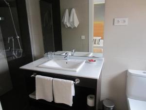 a bathroom with a sink and a mirror and a toilet at Hotel Llorca in Platja de l’Almadrava