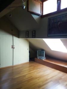 an attic room with a tv and a wooden floor at Little Lodge in Rivisondoli