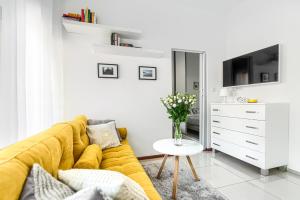 a living room with a yellow couch and a vase of flowers at Apartament Leśny in Wisełka
