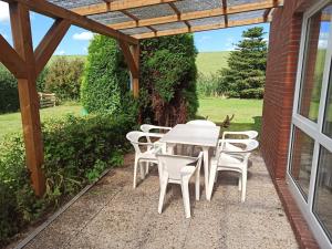 una mesa blanca y sillas bajo una pérgola de madera en Ferienhaus Friesenrose 45237 en Ditzum