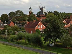 een dorp met huizen en een windmolen op de achtergrond bij Ferienhaus Friesenrose 45237 in Ditzum