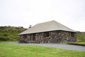 a stone building with a roof on a field at Crofters Cottage in Struan