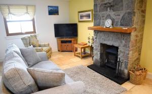 a living room with a stone fireplace and a television at Crofters Cottage in Struan