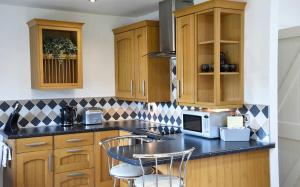 una cucina con armadi in legno e piano di lavoro nero di Crofters Cottage a Struan