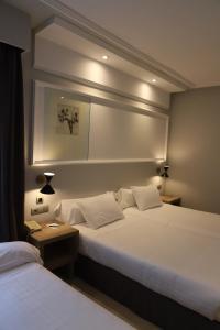 Hotel Olid في بلد الوليد: سريرين في غرفة الفندق مع مصباحين