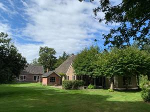 una casa con un patio verde con una casa en Landgoed Olterterp Lodges, kies een comfortabel huisje of appartement op de allermooiste locatie en Olterterp