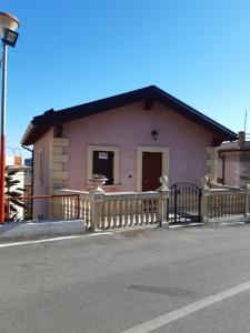 ein kleines rosafarbenes Haus mit einem Holzzaun in der Unterkunft Il Murales Montegiordano in Montegiordano