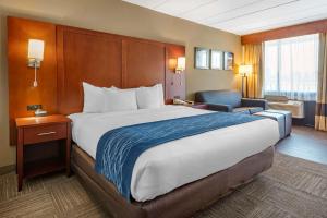 um quarto de hotel com uma cama grande e uma cadeira em Comfort Inn Edgewater on Hudson River em Edgewater