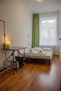 Schlafzimmer mit einem Bett, einem Tisch und einem Fenster in der Unterkunft Simple Seasons Rooms - Самозаселение in Sankt Petersburg