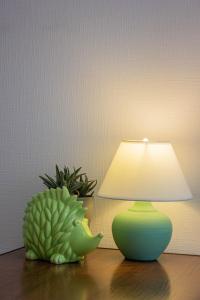 una lámpara verde sentada en una mesa junto a una planta en Simple Seasons Rooms - Самозаселение, en San Petersburgo