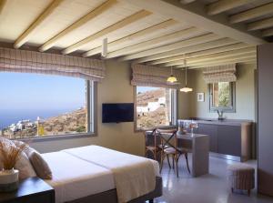 a bedroom with a bed and a kitchen with a table at Aeolis Tinos Suites in Tinos