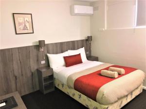 a bed room with a white bedspread and pillows at Bradman Motor Inn in Cootamundra