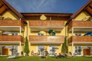 a yellow building with people sitting on chairs in the yard at Hotel Garni Oasis Loipersdorf in Jennersdorf