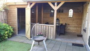 een houten hut met een veranda en een grill bij Sneek Vakantiehuis Verhuur in Sneek