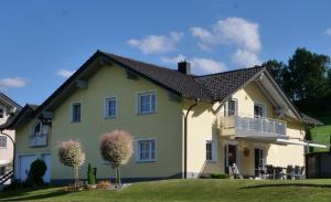 a yellow house with a black roof at Ferienwohnung Rosl in Waldkirchen