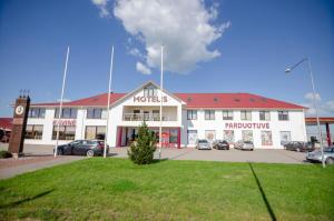 a white building with a clock in a parking lot at Pasienis in Pasvaliečiai