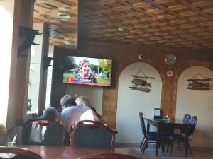 personnes assises à une table dans un restaurant en regardant la télévision dans l'établissement Pasienis, à Pasvaliečiai