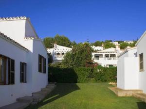 una casa blanca con un patio con césped en Casa Oeste - Family-friendly holiday home with sea view, en Son Bou