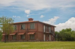 un grand bâtiment en briques avec une terrasse couverte sur un champ dans l'établissement Yerba Buena casas de campo - Arroyo de los Patos, à Nono