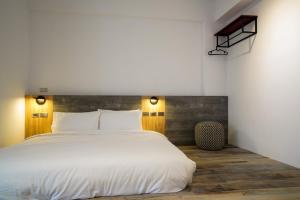 a bedroom with a large white bed with a wooden headboard at Simple Living in Taitung City