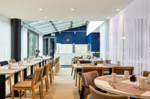 uma fila de mesas e cadeiras num restaurante em Residence Mercure Paris La Defense Grande Arche em Nanterre