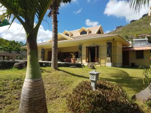 a yellow house with a palm tree in the yard at La Villa Marie Joana in Le Morne