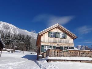 a log cabin in the snow with mountains in the background at Ferienhaus Gaiswinkler in Grundlsee