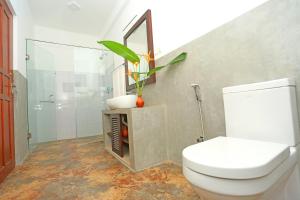 a bathroom with a toilet and a glass shower at Villa Peacock in Galle