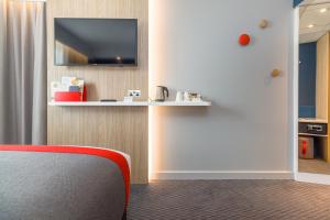 a room with a red chair and a tv on a wall at Holiday Inn Express - Bodmin - Victoria Junction, an IHG Hotel in Bodmin