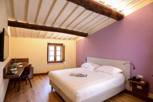 a bedroom with a large white bed and a desk at Castello La Leccia in Castellina in Chianti